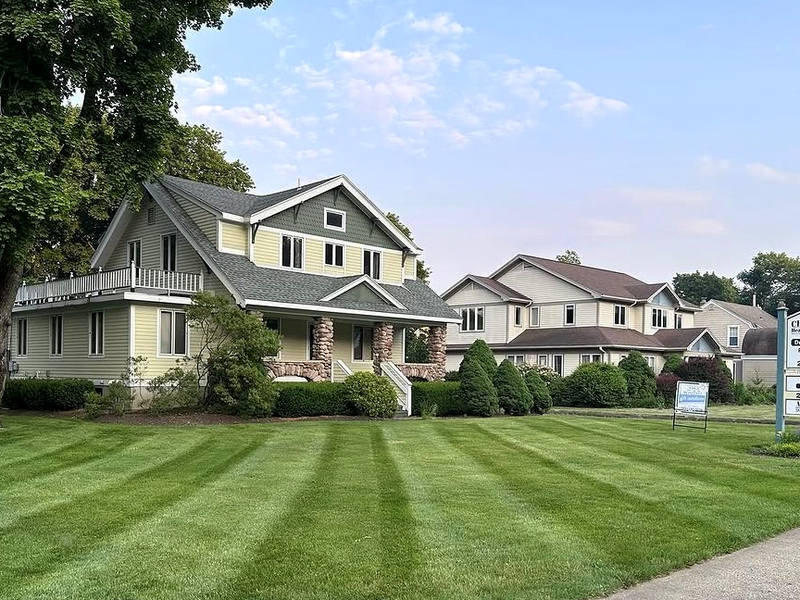 Striped lawn in front of a maintained New England property — Premier Property Maintenance work